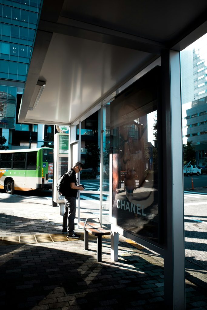 A man standing at a bus stop waiting for a bus